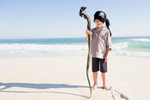 Boy in pirate costume standing on the beach